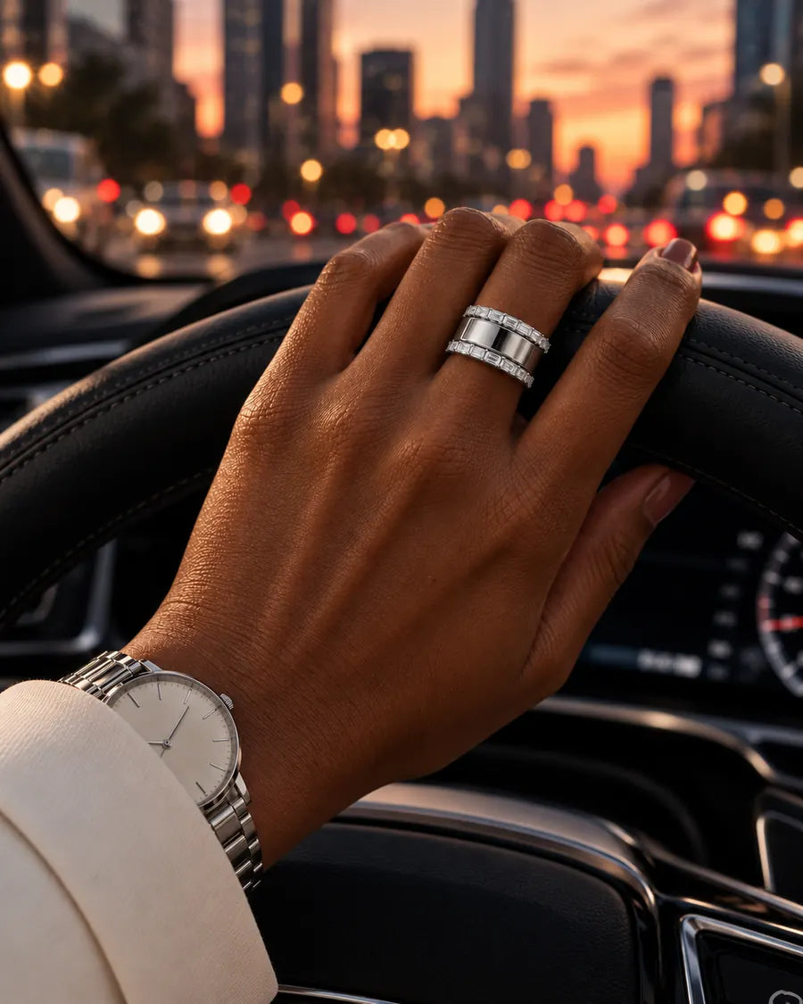 HALO Baguette in 14k white gold, worn over a silver Oura Ring with a hand on the steering wheel on a city drive at dusk
