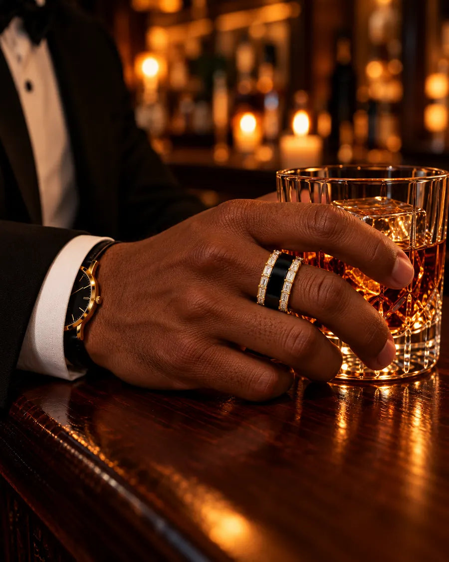 Man in a tuxedo wearing HALO Baguette in 14k yellow gold over a black Oura Ring, holding a whiskey glass