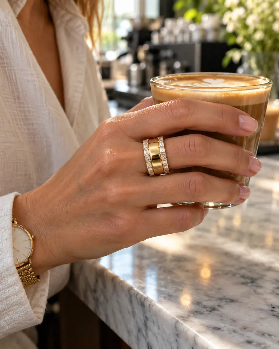 HALO Baguette in 14k yellow gold, worn over an Oura Ring while holding a latte in a sunlit café