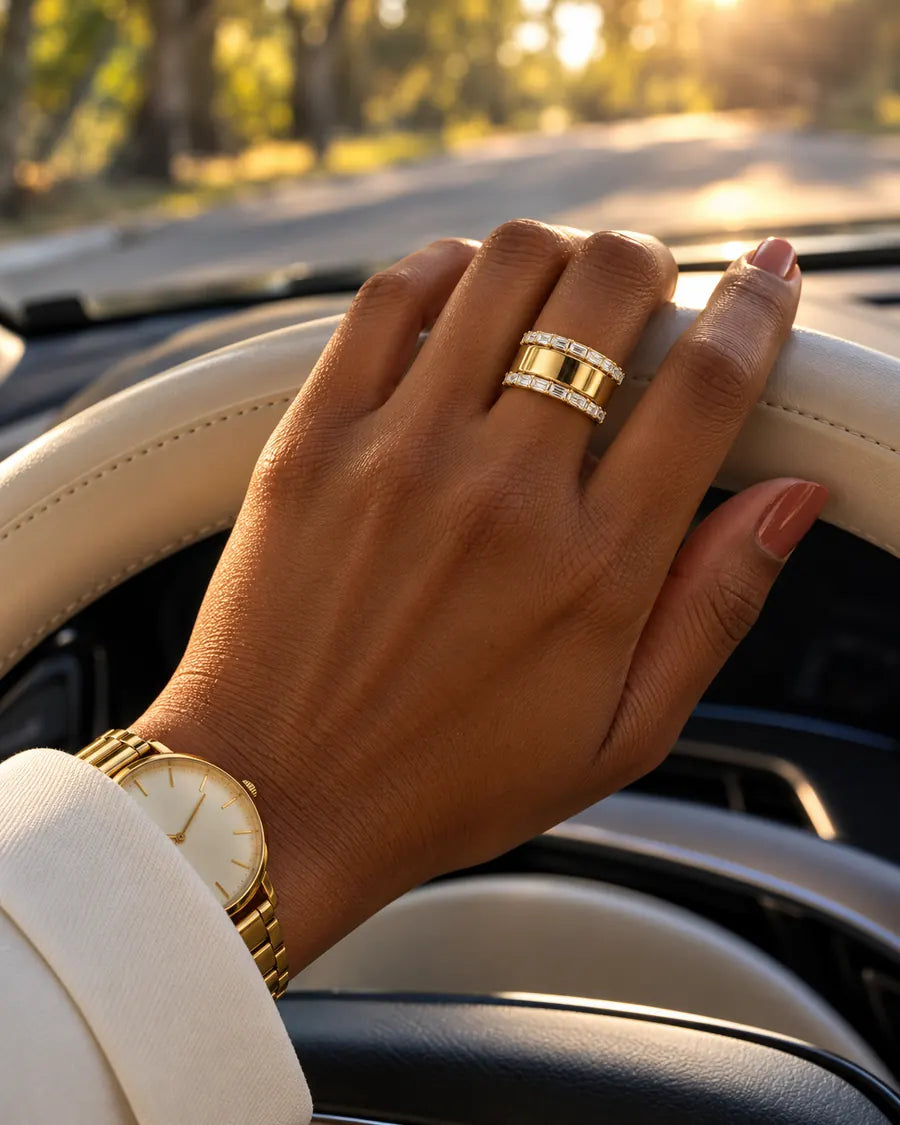 HALO Baguette in 14k yellow gold, worn over a gold Oura Ring with a hand on the steering wheel at golden hour