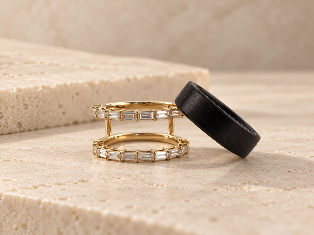 HALO Baguette in 14k yellow gold beside a black Oura Ring on travertine